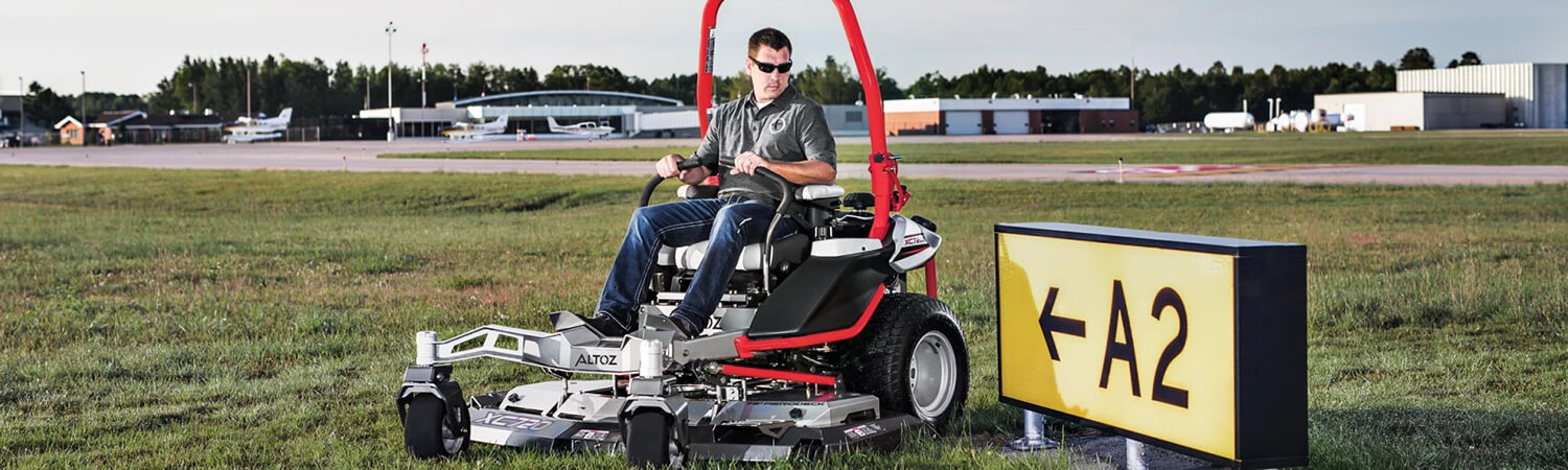Man riding a 2020 Altoz TRX mower in front of an airport